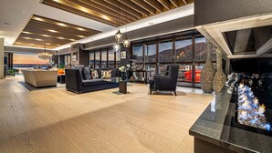 A modern living room with a sofa, armchairs, and a coffee table, large windows with a view, and a fireplace with a stone accent.