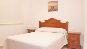 Une chambre à coucher avec un lit en bois, deux tables de chevet, une petite table et un tableau accroché au mur.