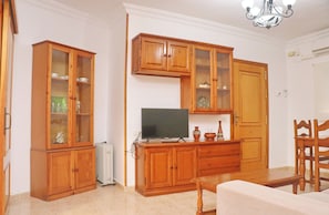 Una sala de estar con armarios de madera, un televisor y una mesa de comedor.