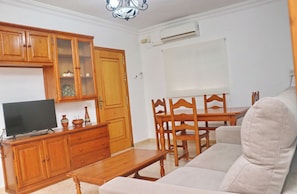 Una sala de estar con muebles de madera, un televisor y un equipo de aire acondicionado.