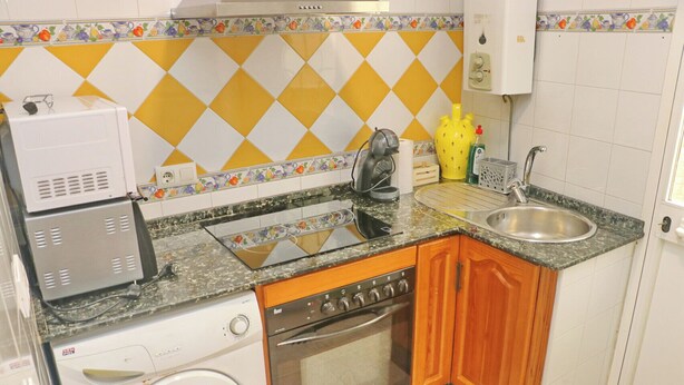 Une cuisine de taille réduite équipée d’un lave-linge, d’une cuisinière et d’un évier.