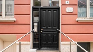 Un edificio rojo con una puerta negra y un buzón pequeño y blanco.