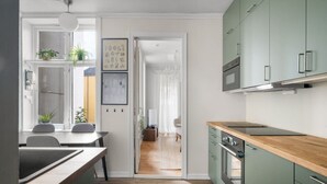 Una cocina moderna con armarios verdes, encimera de madera y un comedor con mesa y sillas.