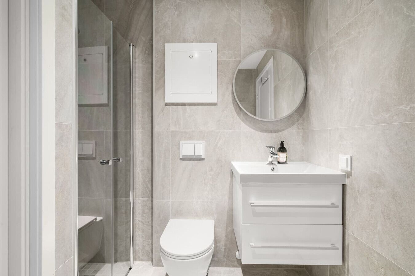 Een moderne badkamer met toilet, wastafel, spiegel en douchecabine.
