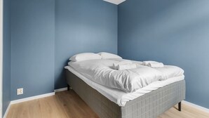 A bedroom with a bed, blue walls, and wooden flooring.