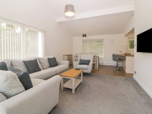 Uma sala de estar moderna com sofá, poltrona, mesinha de centro e um espaço de jantar com cadeira e mesa.