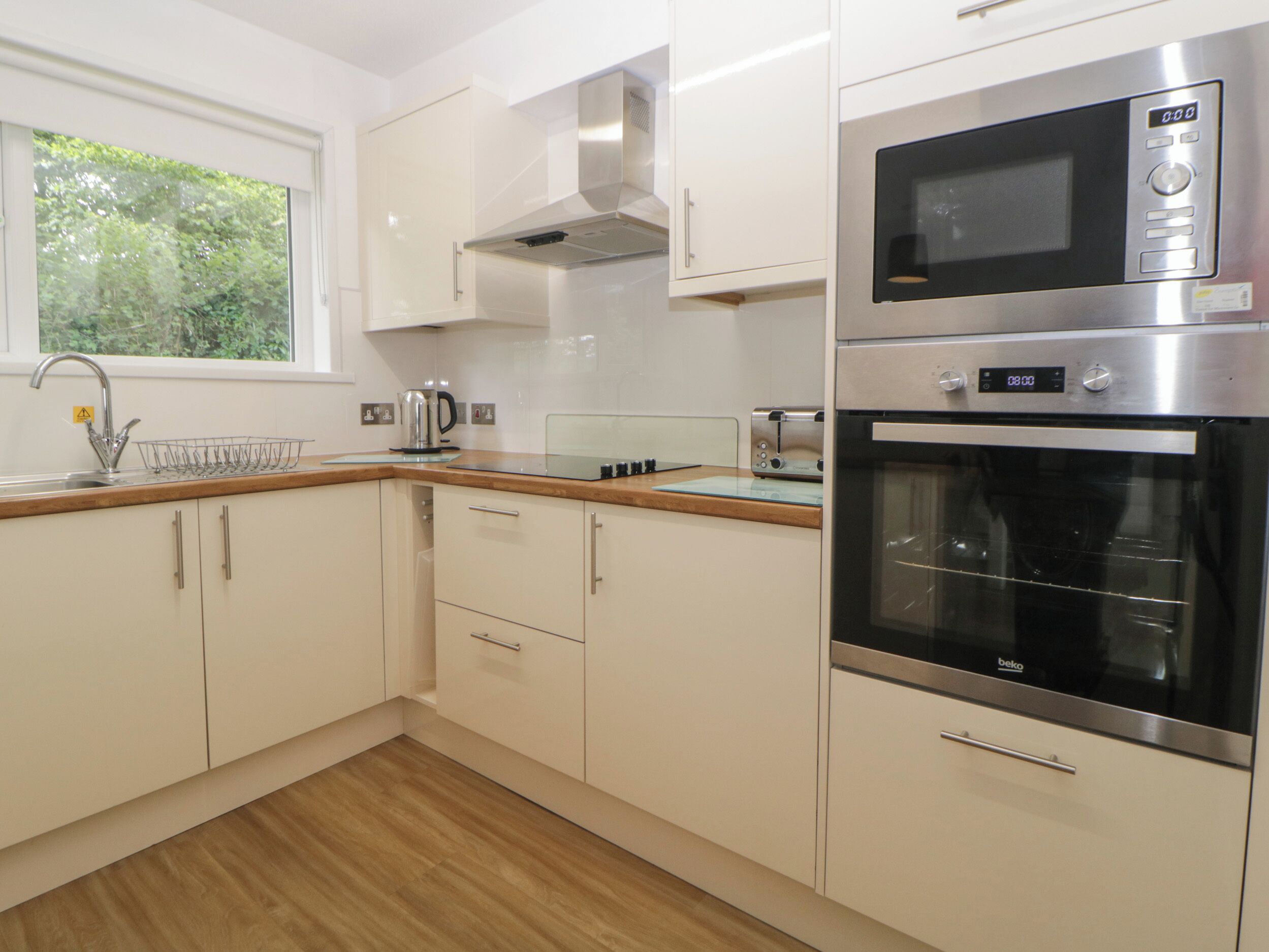 A modern kitchen with white cabinets, a stainless steel microwave, and a built-in oven.