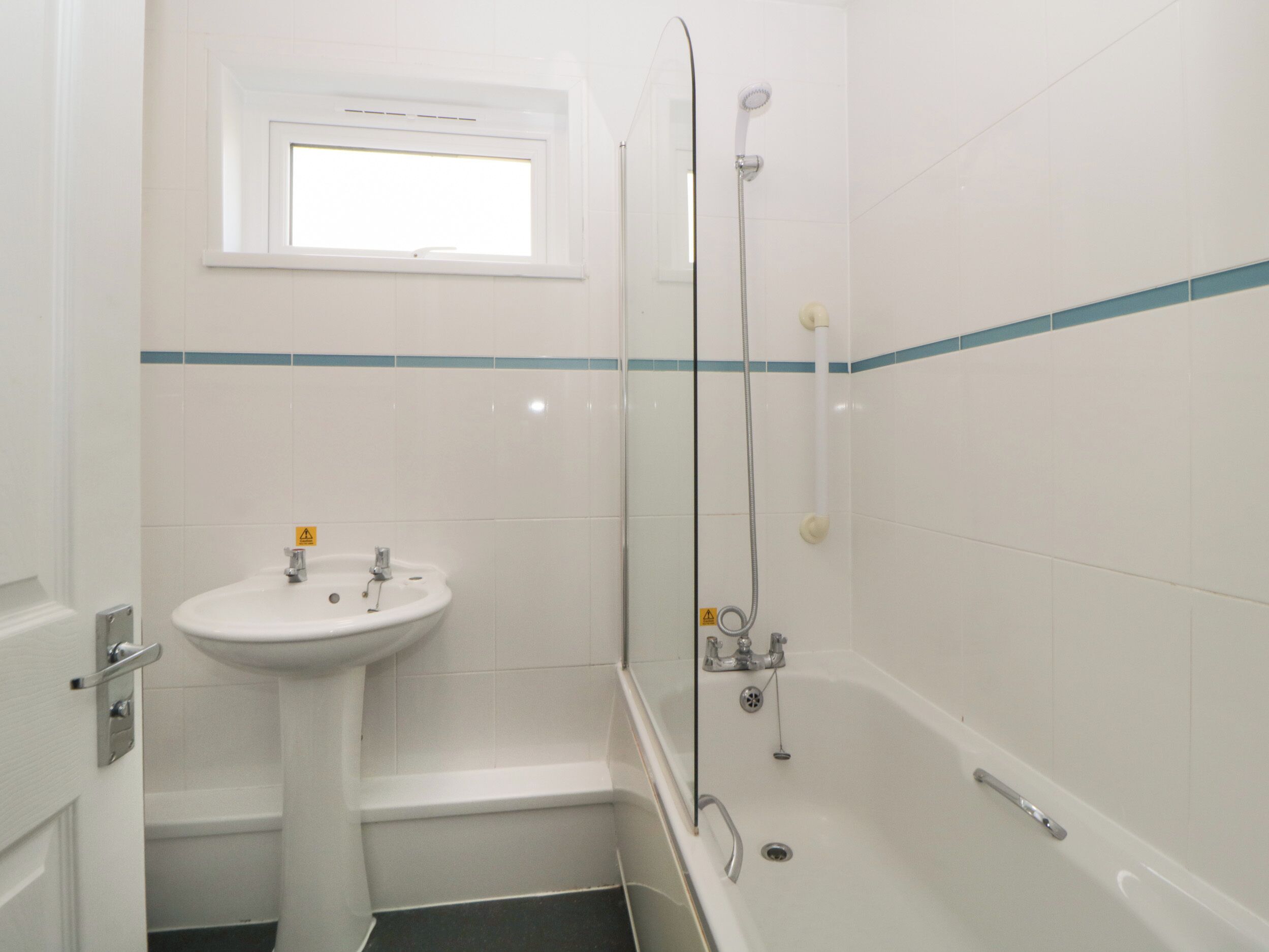 A bathroom with a sink, a shower, and a window.