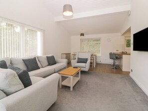 A modern living room with a sofa, armchair, coffee table, and a dining area with a chair and table. - Pebble &amp; Pine at Harcombe House (Newton Abbot)