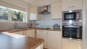 Uma cozinha moderna com bancada de madeira, eletrodomésticos de aço inoxidável e armários brancos.