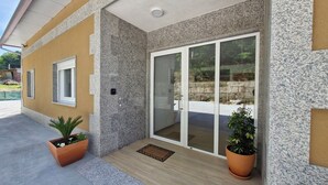 A building facade with a yellow exterior, granite cladding, and a sliding glass door leading to a paved area.