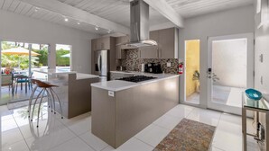 A modern kitchen with a central island, stainless steel appliances, and a large window.