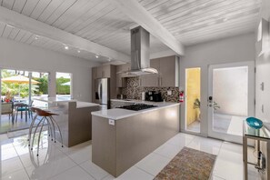 A modern kitchen with a central island, stainless steel appliances, and a large window.