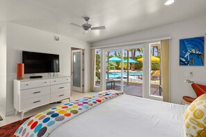 A bedroom with a bed, a TV on a dresser, and a view of an outdoor pool area.
