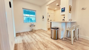 Una cocina moderna con ventana, un cubo de basura y una barra con taburetes.