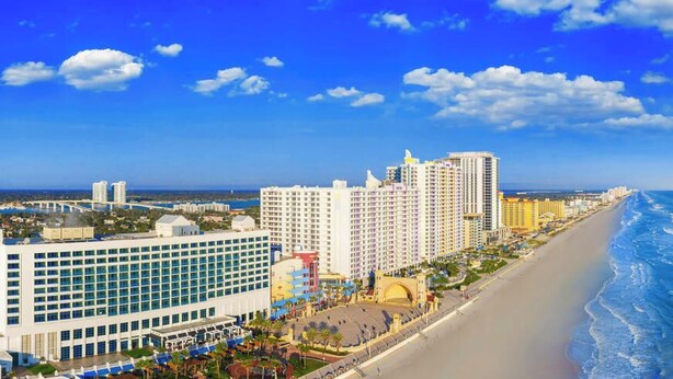 Un hotel costero con varios edificios altos, una playa y un cielo azul despejado.