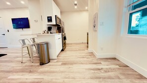 A modern kitchen with a built-in oven, a coffee machine, and a TV displaying a program. - Surfside Siesta on the Strip (Daytona Beach)
