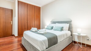 Et pænt arrangeret soveværelse med en seng, et natbord med lampe og et garderobeskab.