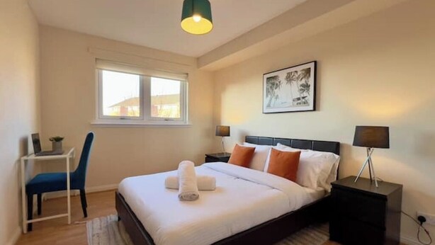 Une chambre bien rangée, avec un lit, des tables de chevet, un bureau et une chaise.