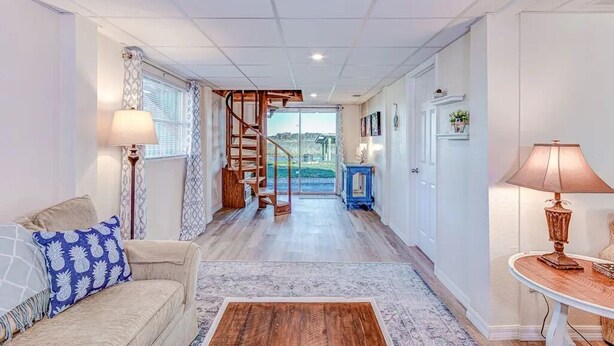 A spacious hallway with a staircase leading to a balcony, a sofa with patterned cushions, and a small table with a lamp. - Lake Side Retreat (Inverness)