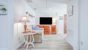 A modern living room with a sofa, a small table, a TV, and a cabinet. - Lake Side Retreat (Inverness)
