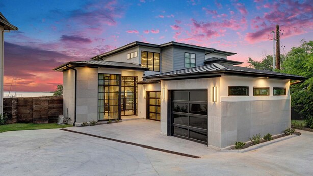 A modern two-story house with a garage, large windows, and a well-maintained lawn.