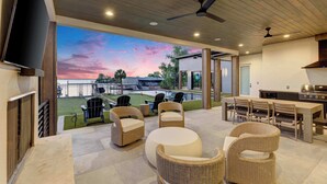 An outdoor patio with wicker furniture, a TV, and a grill area.