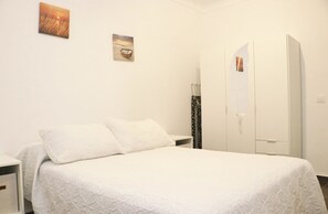 Une chambre à coucher comprenant un lit, une table de chevet, une armoire et deux tableaux accrochés au mur.