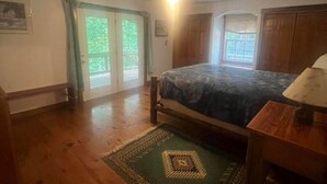 A bedroom with a bed, a ceiling fan, a nightstand, and a view of the outdoors through a sliding glass door.