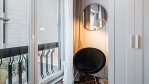 Ein modernes Zimmer mit großem Fenster, einem runden Spiegel, einem schwarzen Stuhl und einem Kleiderschrank.