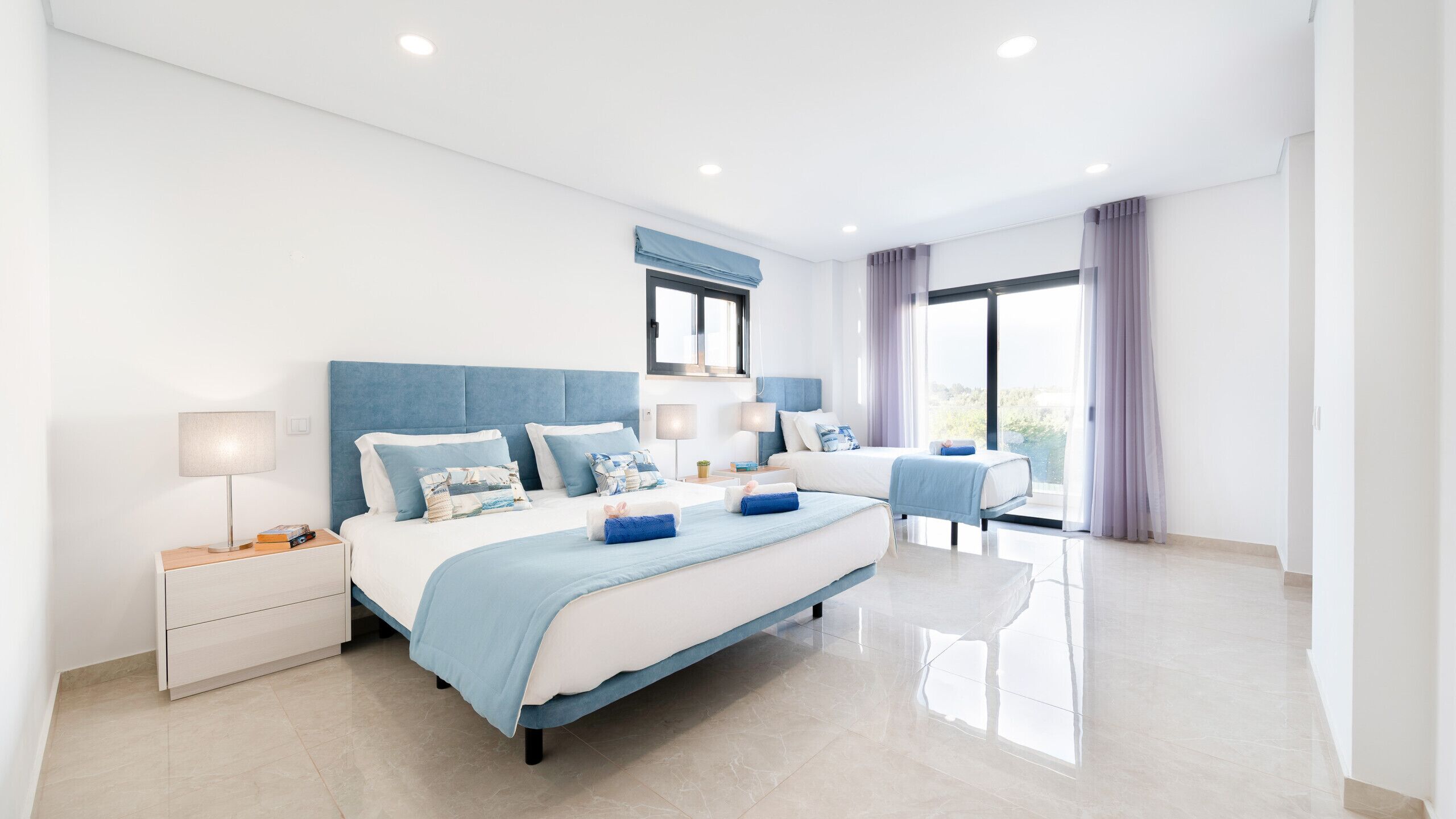 Un dormitorio moderno con una cama grande, mesitas de noche y vistas al exterior.