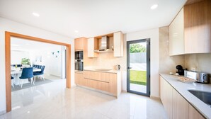 A modern kitchen with wooden cabinets, a built-in oven, and a toaster. - Villa Lion Beach (Albufeira)