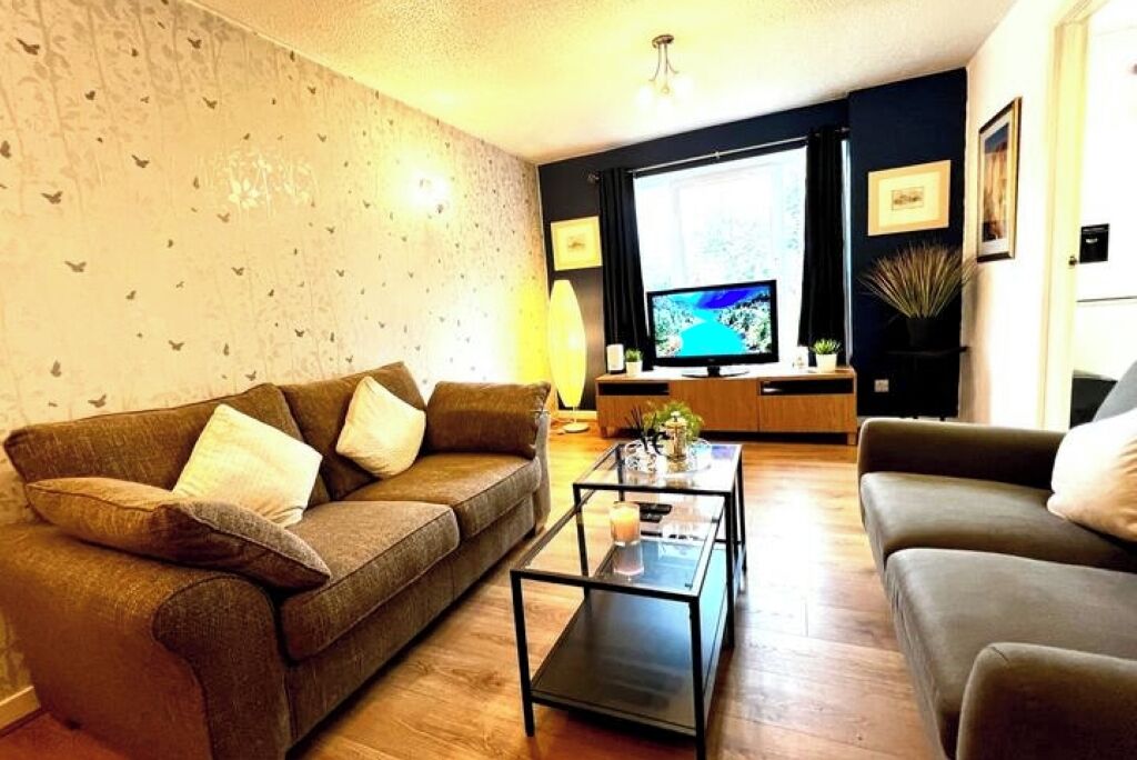 A living room with a sofa, a coffee table, a TV, and a plant.