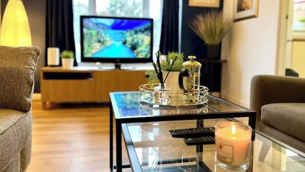 Un soggiorno moderno con un tavolino in vetro, una televisione e un divano.