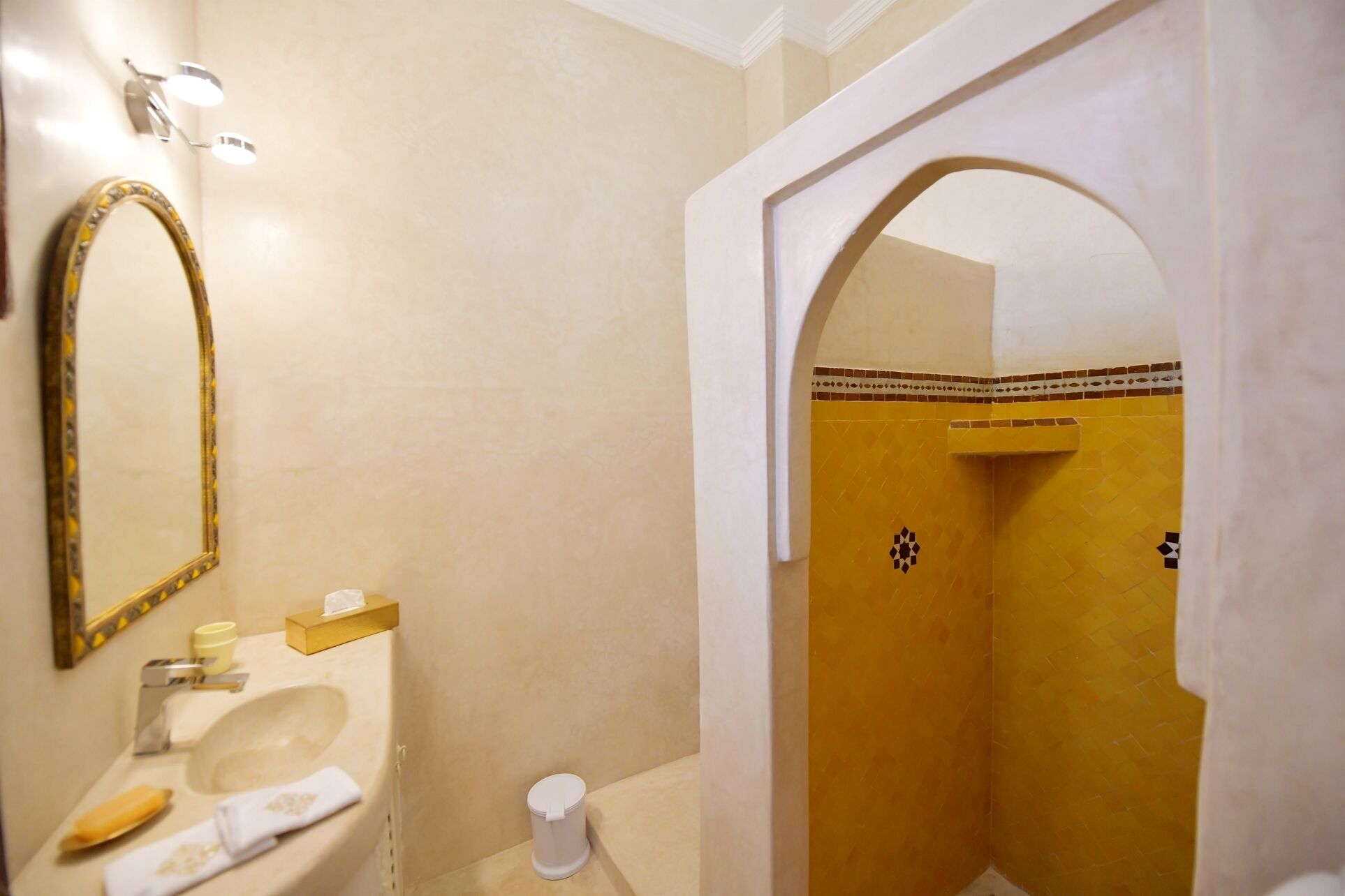 A bathroom with a sink, mirror, and a shower area with tiled walls.