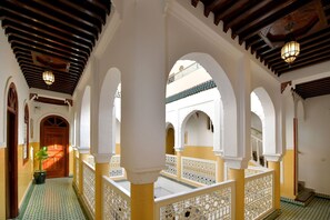 Un pasillo con arcos y techo de madera, que conduce a una habitación con puerta de madera.