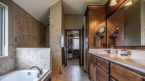 Un baño moderno con un espejo grande, una bañera y un vestidor.