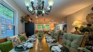 A dining area with a long table set for a meal, surrounded by upholstered chairs.