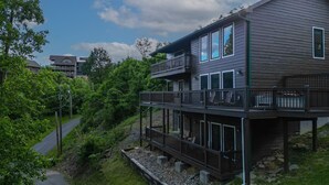 A two-story building with a balcony on the upper level, surrounded by greenery.
