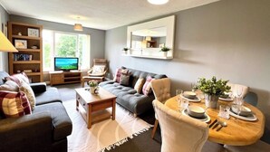 Ein modernes Wohnzimmer mit Sofa, Couchtisch und Essbereich.