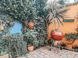 A patio area with a barbecue grill, potted plants, and a blue wall.