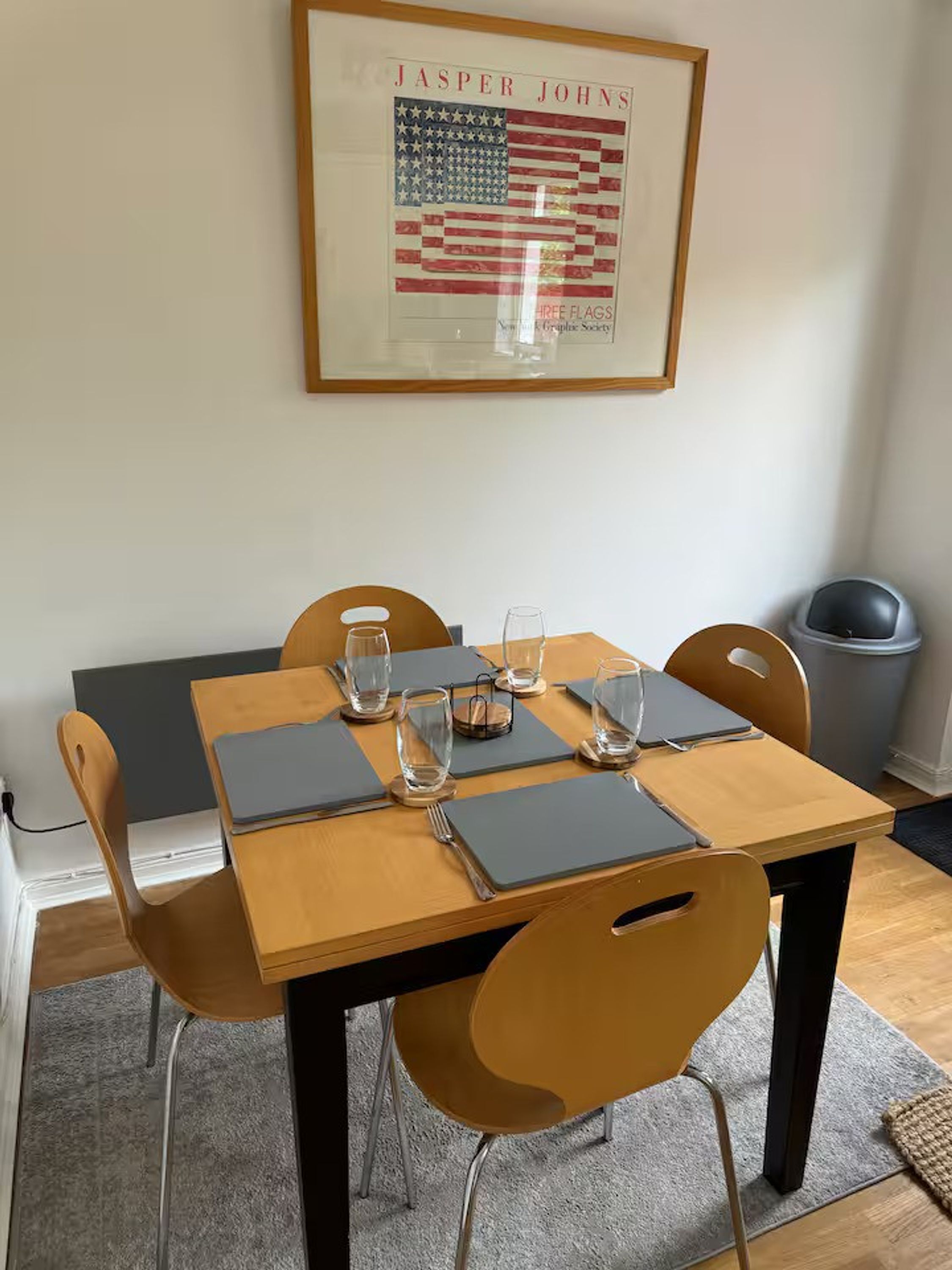 A dining area with a wooden table set for four, including glasses and cutlery.