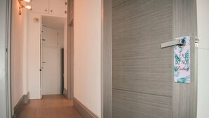 A hallway with a wooden floor, a white door with a 'Please Do Not Disturb' sign, and a light fixture on the left. - The Twickenham Apartment Near Strawberry Hill (Twickenham)