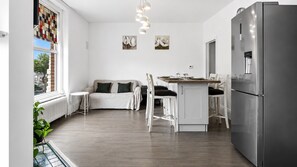 A modern kitchen with a refrigerator, dining table, and chairs. - The Twickenham Apartment Near Strawberry Hill (Twickenham)
