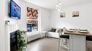 A modern kitchen with a dining area, a fireplace, and a view of the street. - The Twickenham Apartment Near Strawberry Hill (Twickenham)