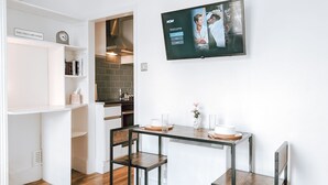 Une cuisine moderne avec un coin repas, un téléviseur fixé au mur et une bibliothèque agrémentée d’une étiquette.