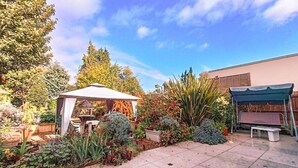 Ein Garten mit einem Pavillon, Terrassenmöbeln und verschiedenen Pflanzen.