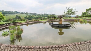 A circular pond with a central fountain, surrounded by a brick walkway and lush greenery. - Harcombe House Rooms Accessible Ground Floor Twin (Newton Abbot)
