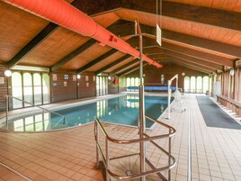 Una piscina interior con techos altos, suelo de baldosas y un puesto de socorrista.
