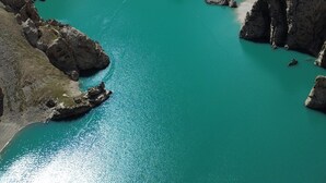 Un paisaje montañoso con un lago turquesa rodeado de acantilados rocosos.